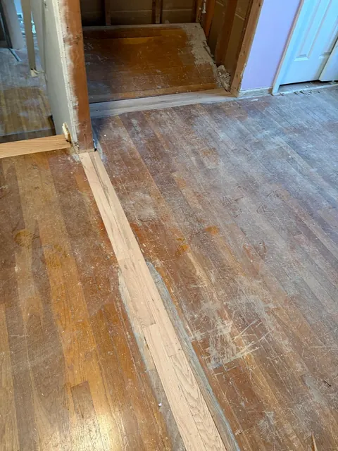 Old hardwood hallway with patched boards before refinishing